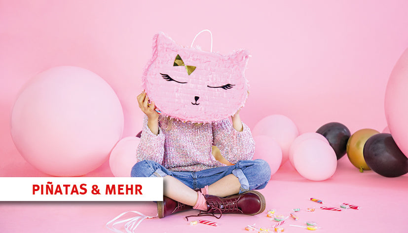 „Kind sitzt im Schneidersitz auf einem rosa Hintergrund und hält eine pinke Katzen-Piñata vor das Gesicht. Umgeben von bunten Luftballons und verstreuten Süßigkeiten. Text im Bild: ‚PIÑATAS & MEHR‘. Link führt zur Shop-Kategorie für Piñatas und passendes Zubehör.